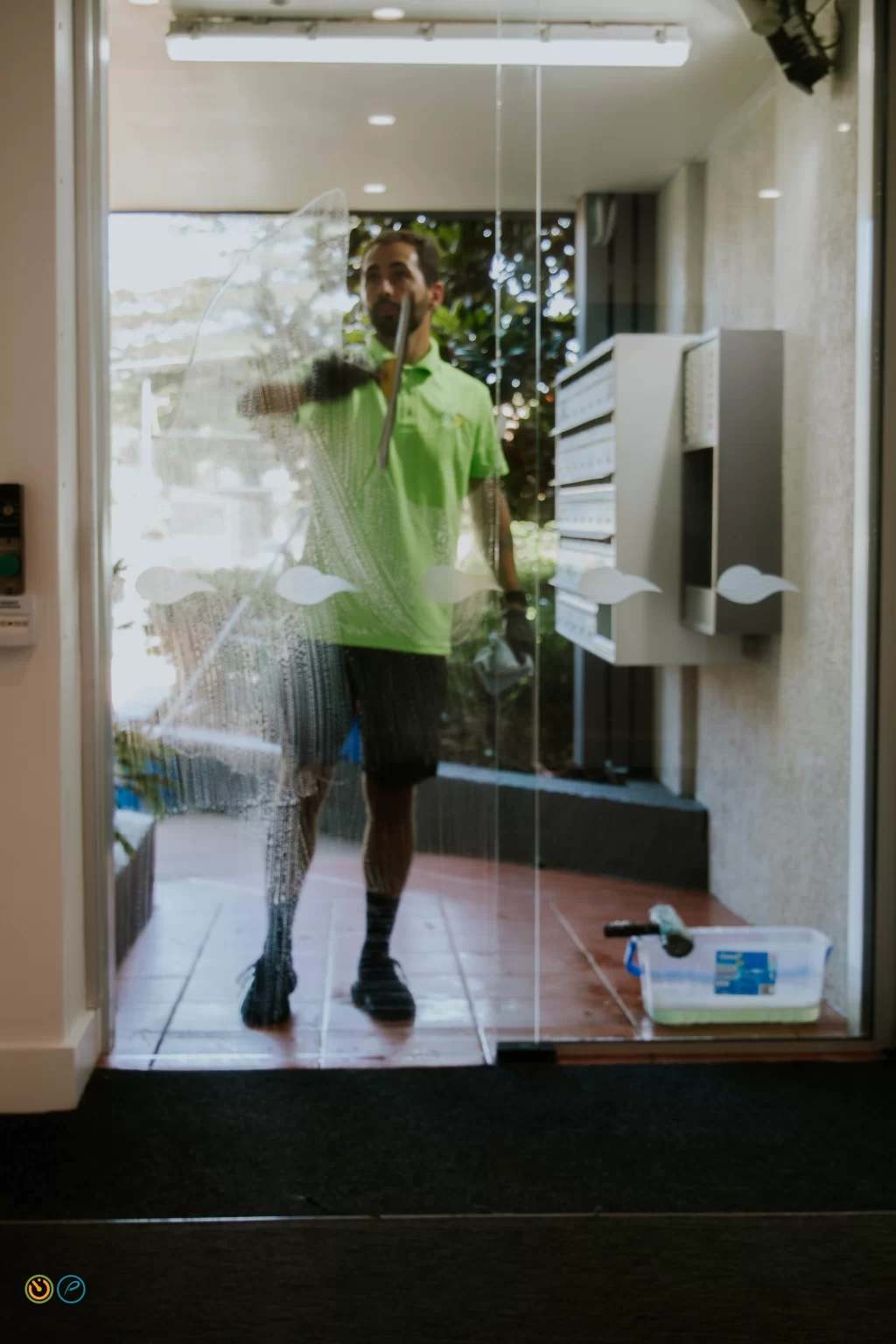 Commercial cleaning professional washing glass entry door at an office building.