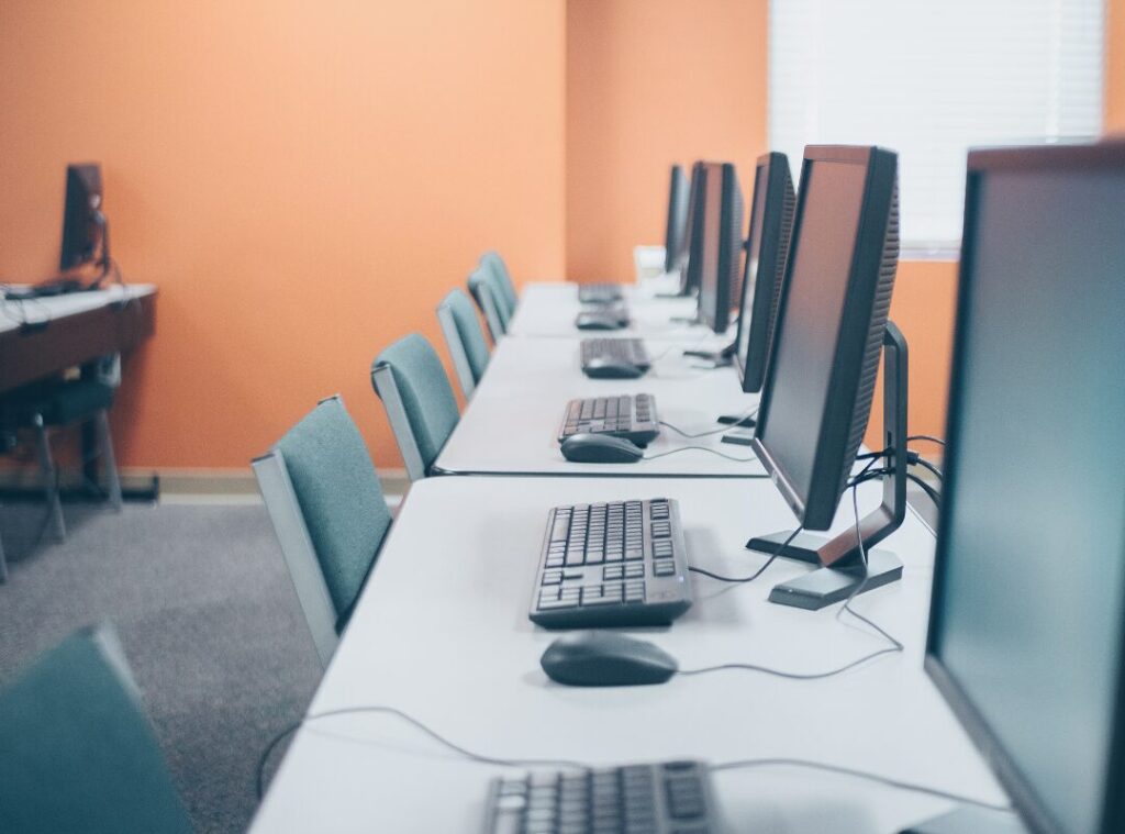 Shared office computers and keyboards lined up on desks, highlighting office hygiene in high-touch work areas.
